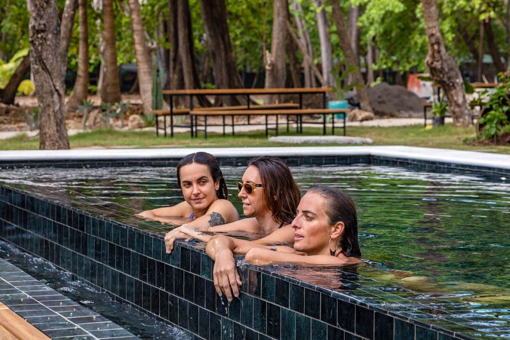 Three people relaxing in an infinity pool at Casa Teresa Luxury Villas in Santa Teresa, Costa Rica