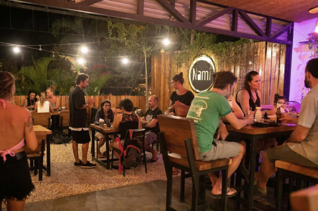 People enjoying outdoor dinner at night in a tropical setting.