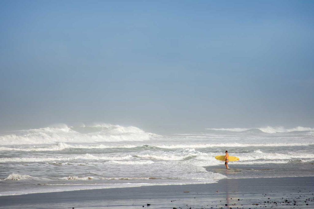 surfer with yellow surfboard walking into the waves