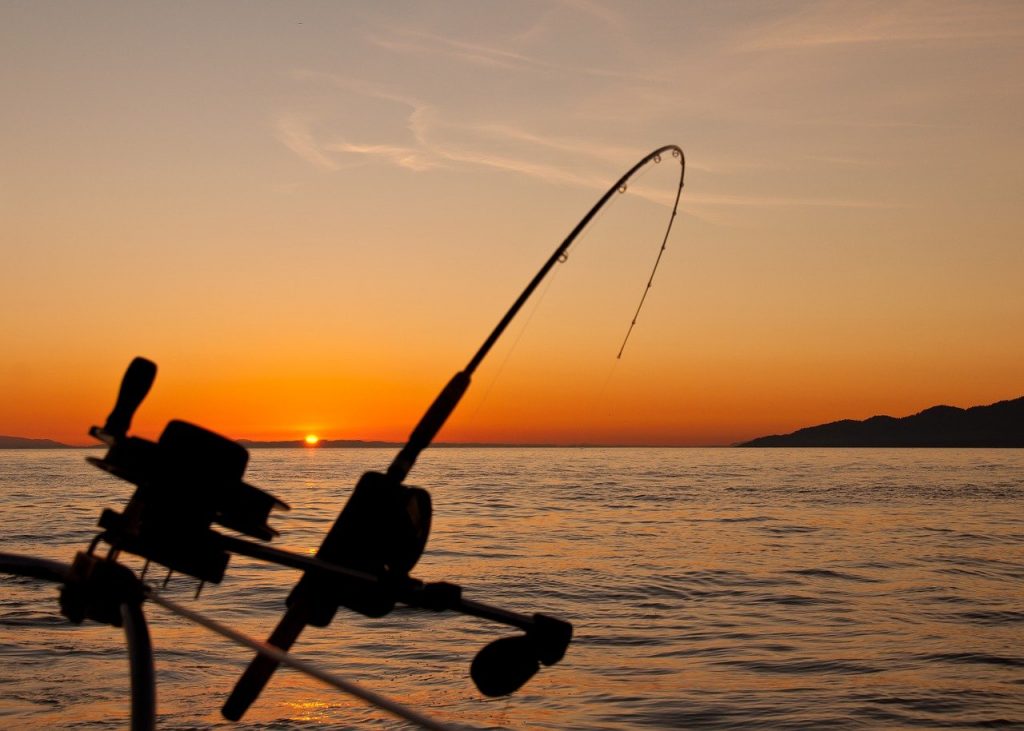A fishing rod suspended off an angling boat at sunset