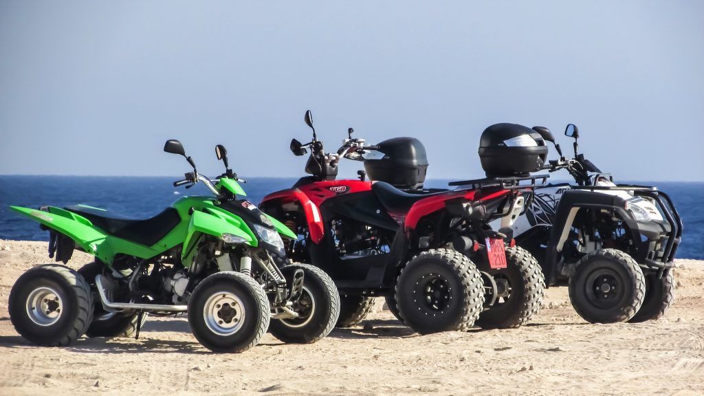 Three all-terrain vehicles on the sand at the beach