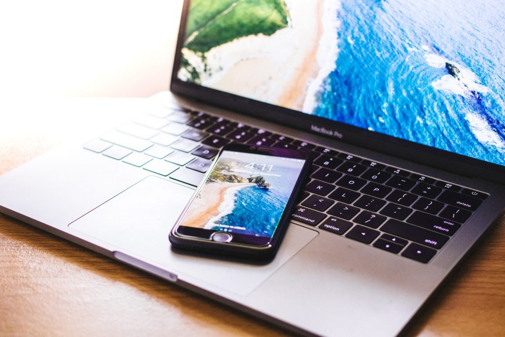 Photo of a laptop and smart phone with tropical beach on their home screens