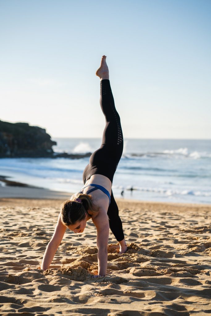 woman practicing yoga on the beach sand