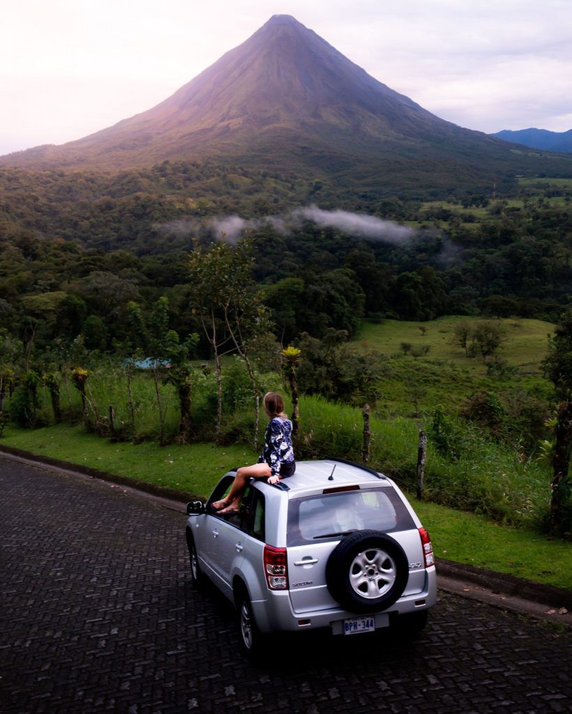 Woman sitting on top of SUV on a tour around Costa Rica