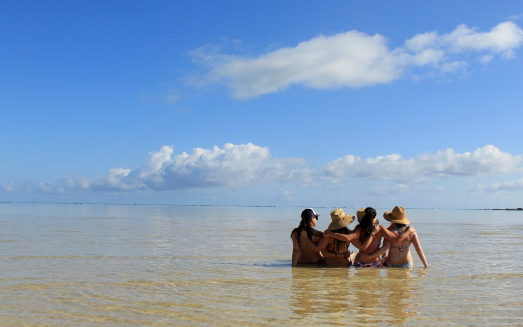 four female friends sitting in the sand at sunny beach