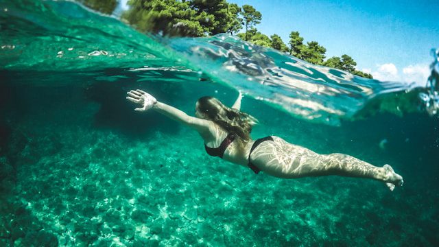 Woman swimming underwater in the waves along a tropical beach