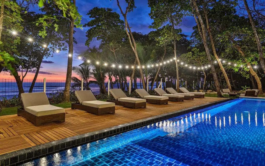 Photo of Casa Teresa Luxury Villas at sunset facing the ocean with an infinity pool, string lights, and lounge chairs