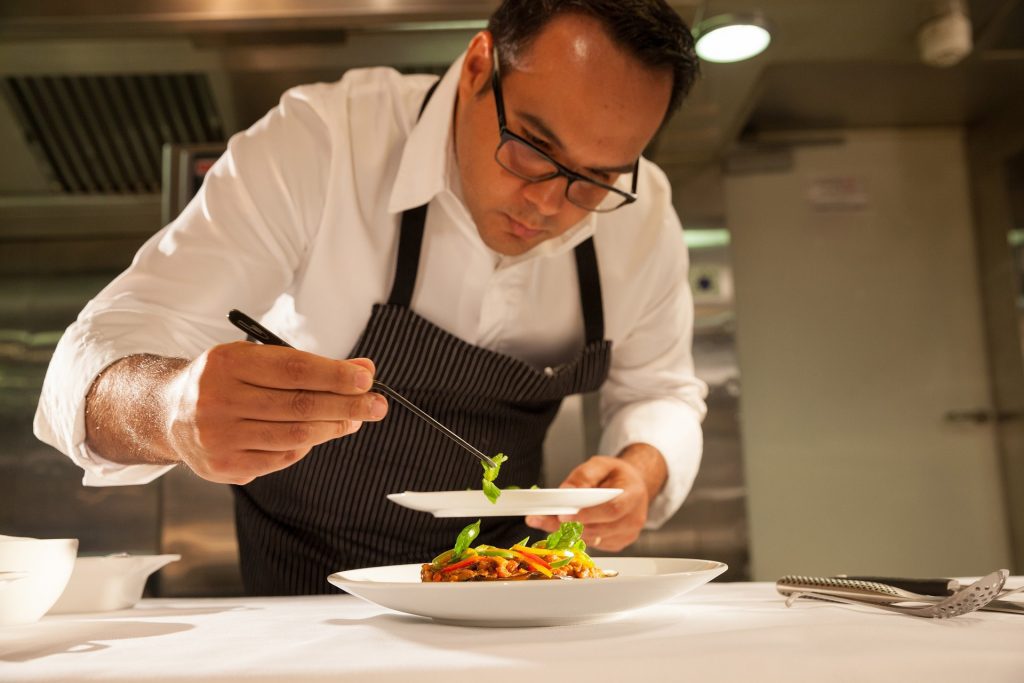 Well dressed chef puts food on a plate