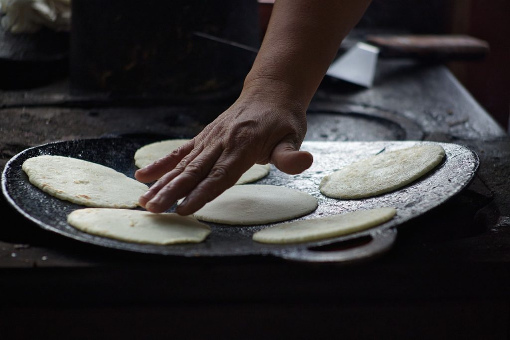 Cook’s hand testing tortillas as they cook in a kitchen in Costa Rica