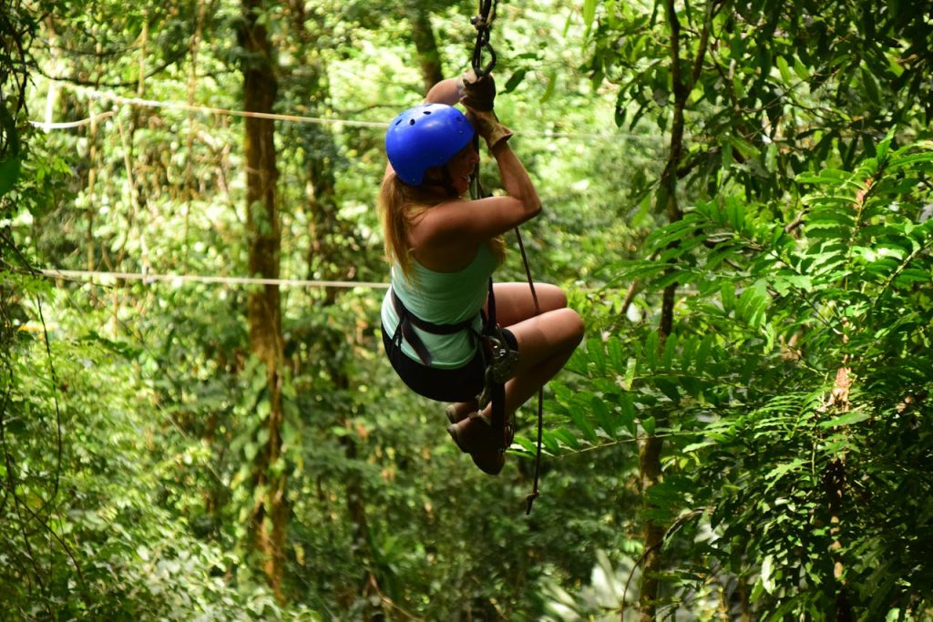 Woman wearing helmet on a zip line moving through jungle canopy in Costa Rica