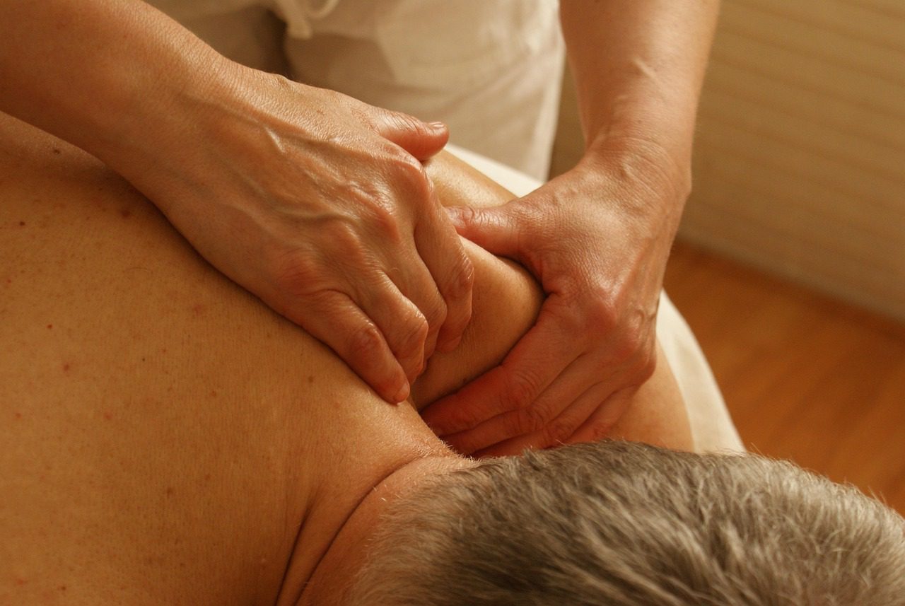 Massage therapist providing deep tissue massage for a man’s neck and shoulders