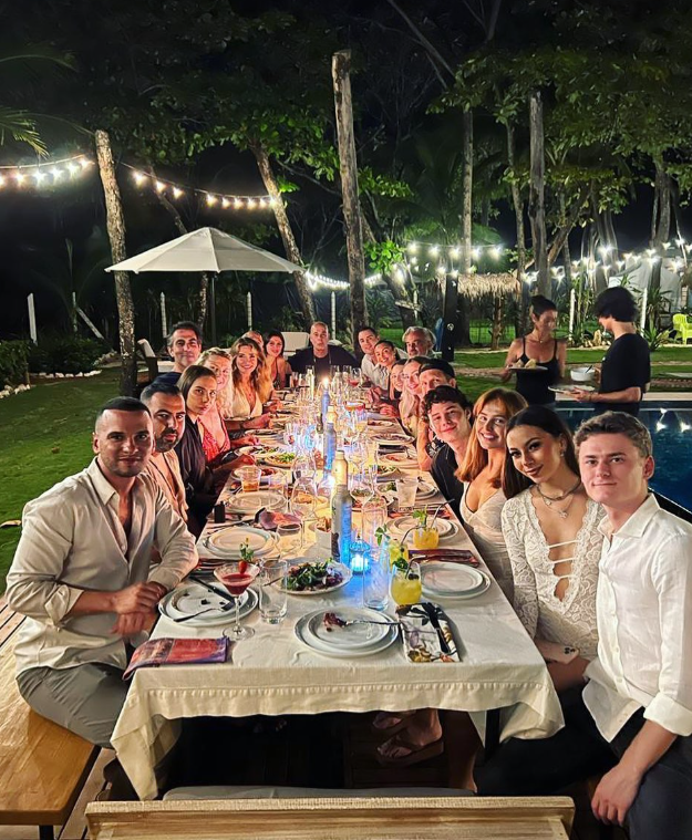 Group of people dining together for dinner at a long table at luxury property Casa Teresa Luxury Villas