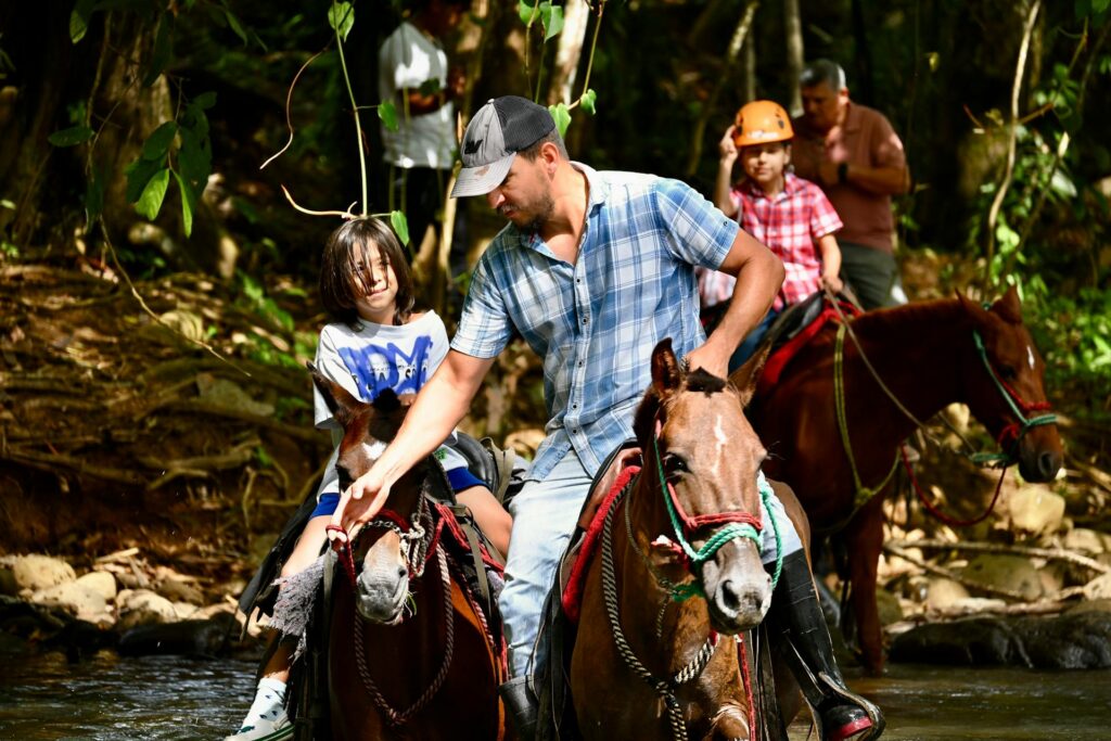 A family with young kids traveling through the Costa Rican jungle on a guided horseback ride