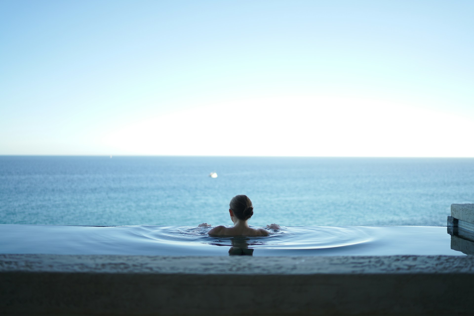 Guest relaxing in an infinity pool overlooking the ocean during a luxury wellness vacation